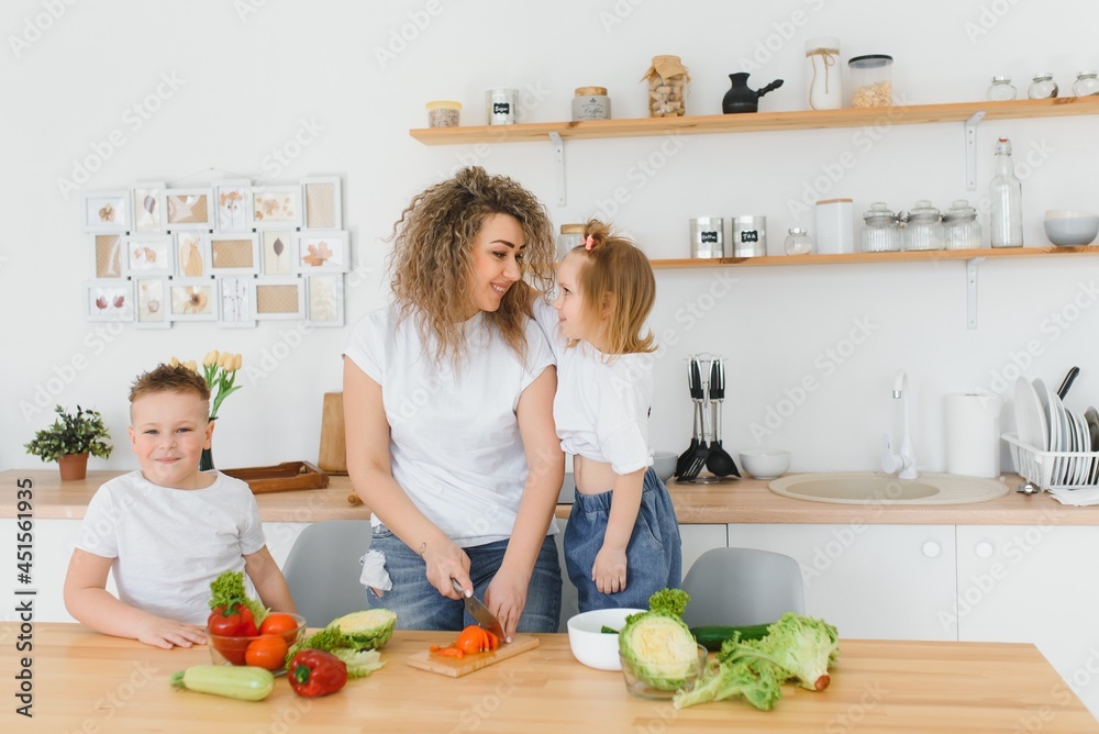 Family in a kitchen. Beautiful mother with children. Lady in white blouse. Family in a kitchen. Beautiful mother with children. Lady in white blouse.