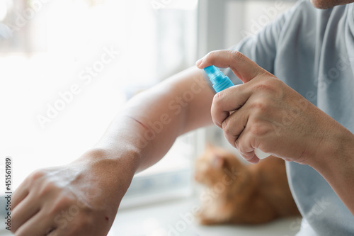 A man is spraying alcohol on a cat scratch wound Cleaning and disinfection : First aid concept in home