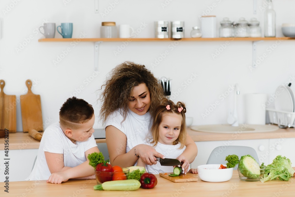 Family in a kitchen. Beautiful mother with children. Lady in white blouse. Family in a kitchen. Beautiful mother with children. Lady in white blouse.