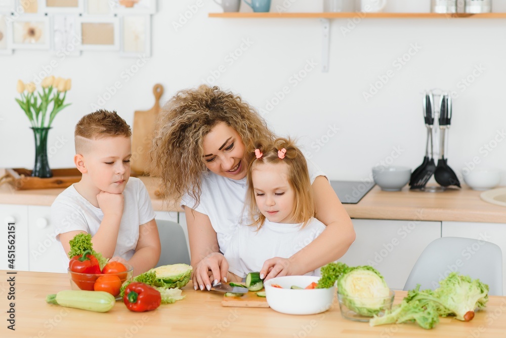 Family in a kitchen. Beautiful mother with children. Lady in white blouse. Family in a kitchen. Beautiful mother with children. Lady in white blouse.