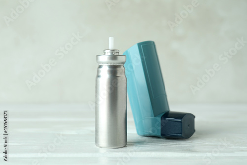 Blue asthma inhaler on white wooden table