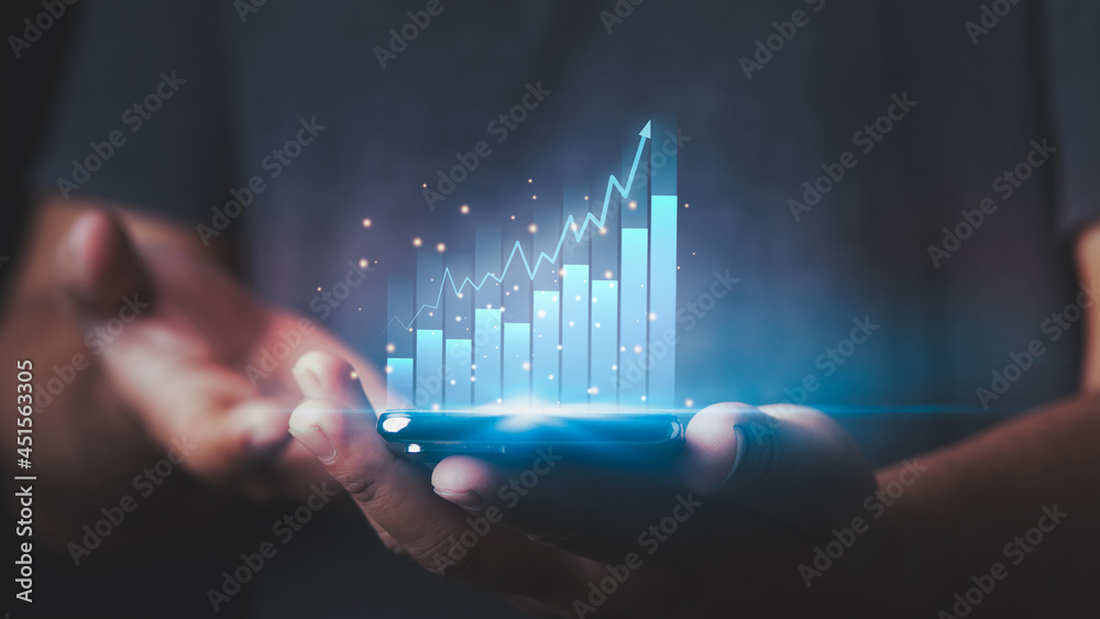 Hand of Businessman or trader is showing a growing virtual hologram stock on a smartphone, invest in trading. The stock market, Business growth, progress, or success concept. Hand of Businessman or trader is showing a growing virtual hologram stock on a smartphone, invest in trading. The stock market, Business growth, progress, or success concept.