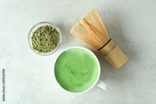 Matcha latte and accessories for making on white textured table