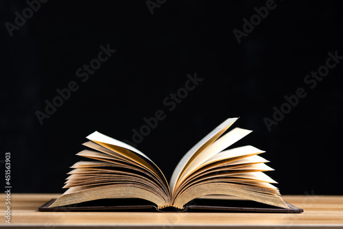 Open book middle page on wooden table isolated on black background.