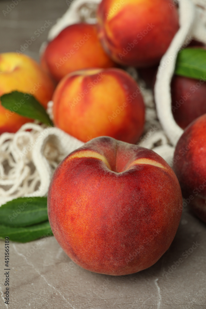 String bag with peach fruits on gray textured table String bag with peach fruits on gray textured table