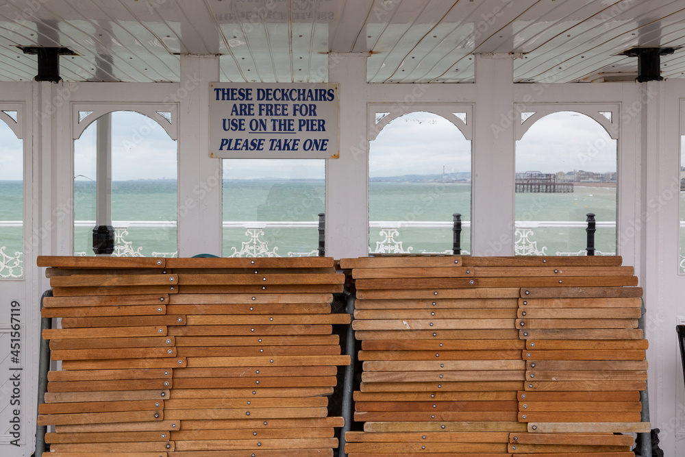 A sign above deck chairs on a pier reading that deckchairs are free to use on the pier at the British seaside A sign above deck chairs on a pier reading that deckchairs are free to use on the pier at the British seaside