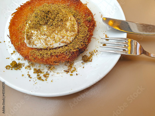 Famous Turkish delicious dessert hot kunefe served with pistachio powder and ice cream. Kunafa or Kunefeh well known Middle Eastern dessert made of goat milk. photo