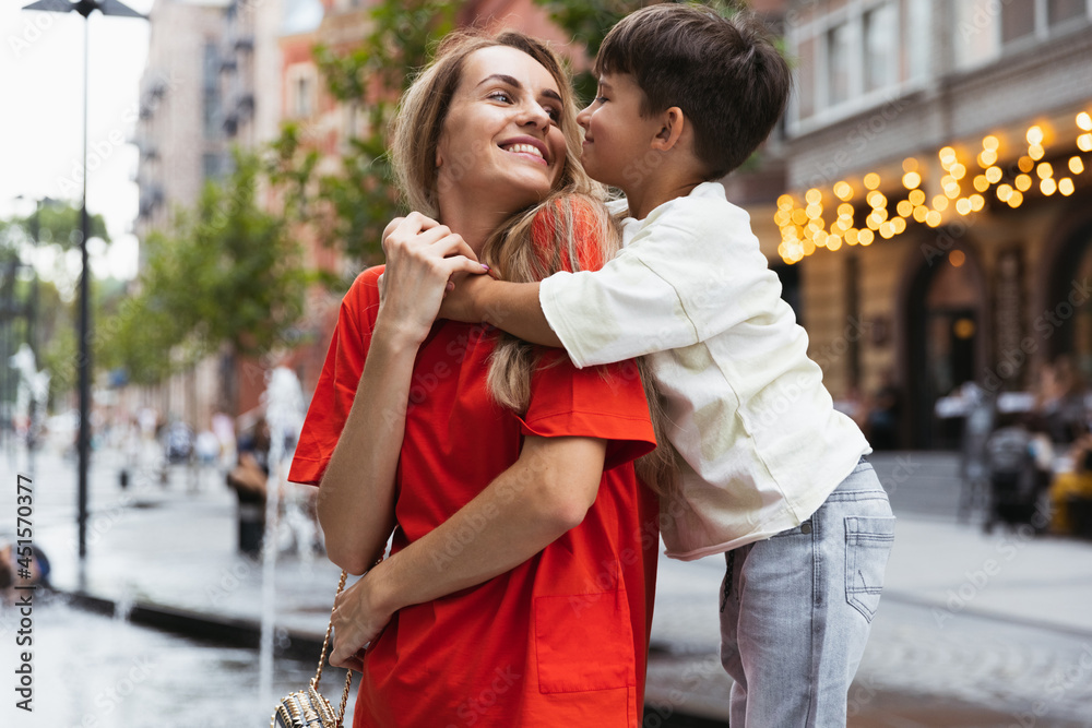 Two people, mother and little cute son strolling at street, trade square in summer time, outdoors. Family time, togehterness, parenting and happy childhood concept.