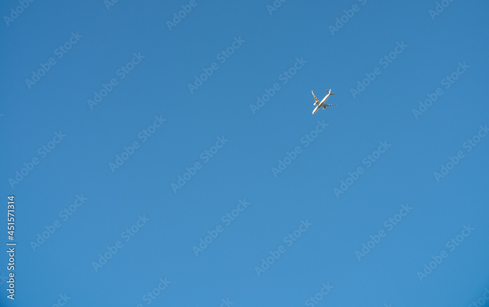 Airplane in a clear blue sky flies from right to left. Passenger or cargo transportation. There is space to add text. Airplane in a clear blue sky flies from right to left. Passenger or cargo transportation. There is space to add text.