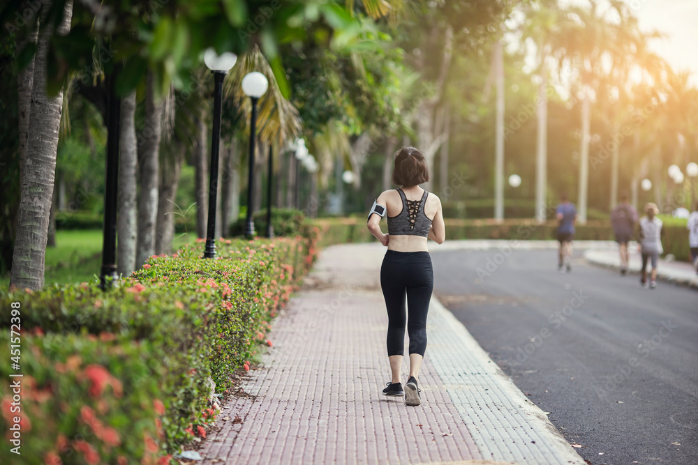 Behind young woman in sportswear jogging running in park outdoor. Healthy female exercise running on the morning.