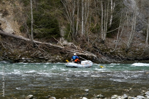 Man rafting with his dog in a rubber boat on river Rhine in Safiental, Switzerland on early spring.