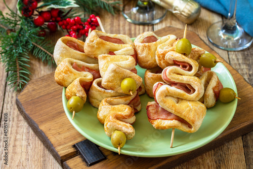 Christmas and New Year food. Holiday snack puff dough Christmas tree with olive and bacon on a wooden table.