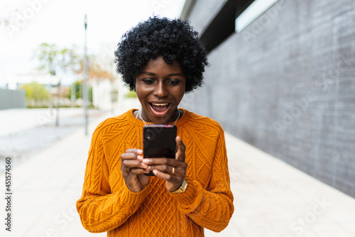 Young african girl happy using her mobile phone outdoors