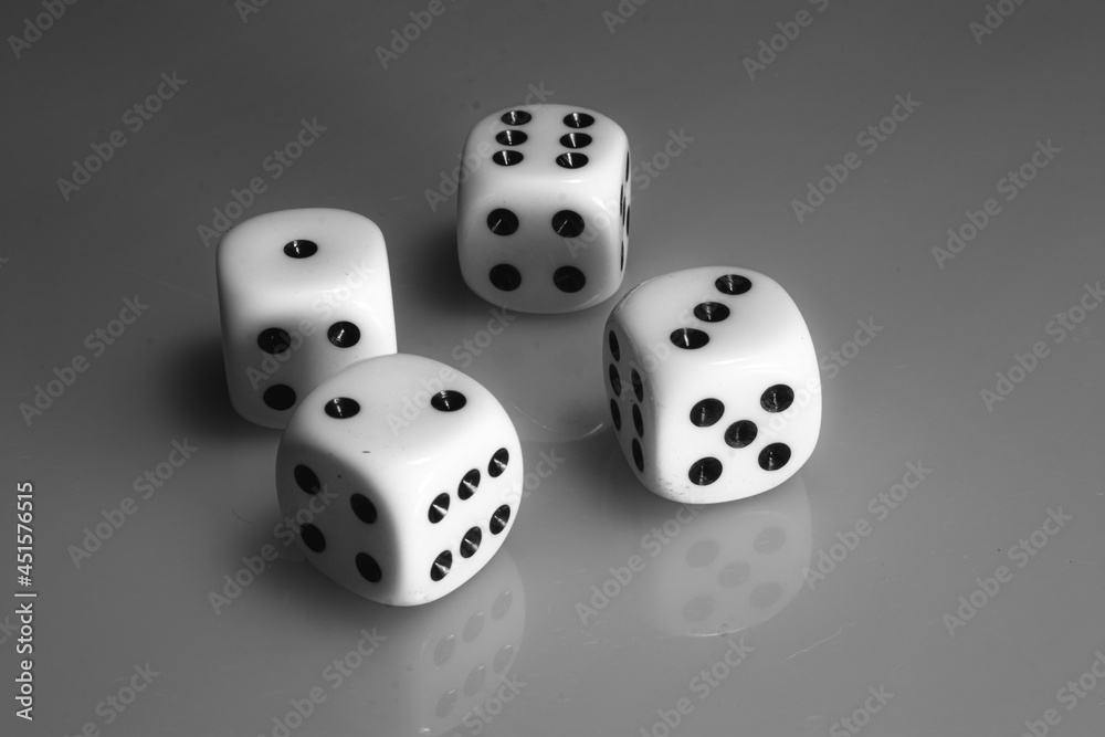 Black and white photo of four white dices for gambling on a matt reflective surface Black and white photo of four white dices for gambling on a matt reflective surface