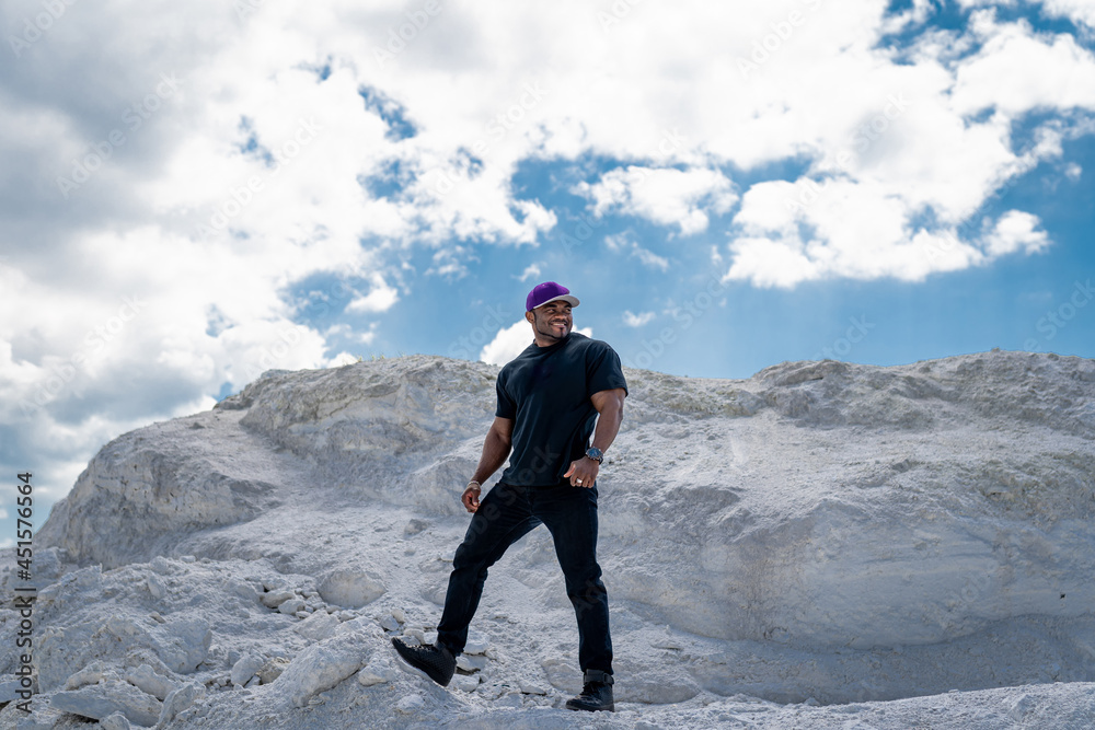 Attractive handsome muscle man with great biceps wearing t shirt looking away and posing to the camera. American cheerful man. Full length view Attractive handsome muscle man with great biceps wearing t shirt looking away and posing to the camera. American cheerful man. Full length view