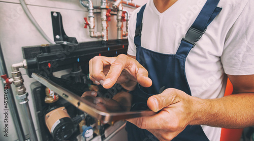The technician checking the heating system in the boiler room with tablet in hand