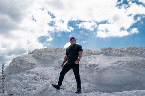 Attractive handsome muscle man with great biceps wearing t shirt looking away and posing to the camera. American cheerful man. Full length view