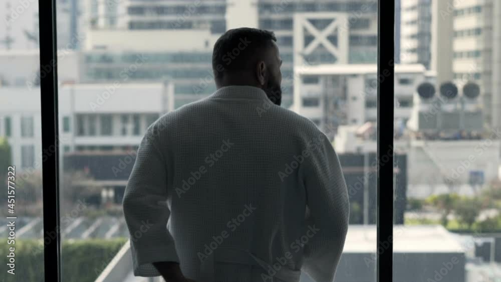 Young man in bathrobe admire view from window at home Young man in bathrobe admire view from window at home