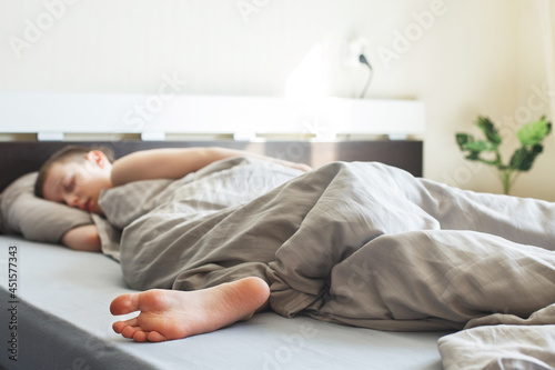 boy sleep sweetly in the bed in the morning. child lies on pillow under blanket