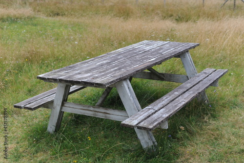 Wooden table and benches for outdoor dining and picnic on a grass field at the camping