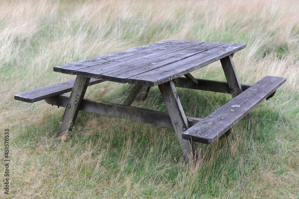 Wooden table and benches for outdoor dining and picnic on a grass field at the camping Wooden table and benches for outdoor dining and picnic on a grass field at the camping
