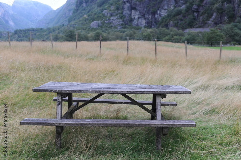 Wooden table and benches for outdoor dining and picnic on a grass field at the camping Wooden table and benches for outdoor dining and picnic on a grass field at the camping