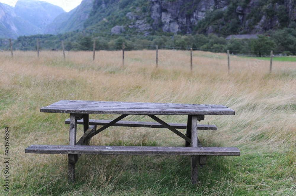 Wooden table and benches for outdoor dining and picnic on a grass field at the camping