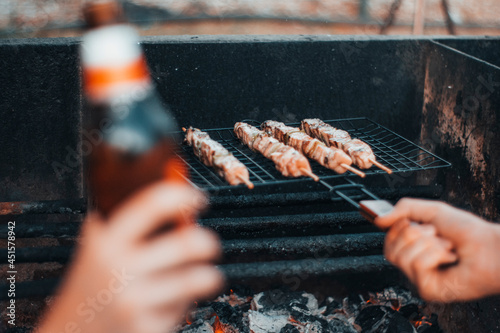 Gente en una barbacoa haciendo unos pinchitos de pollo junto al fuego photo