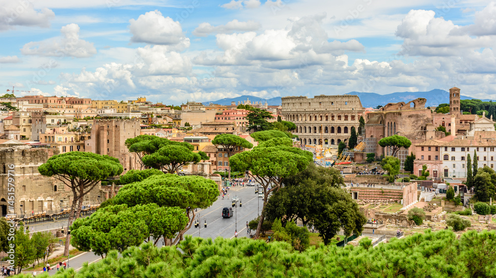Road leading to the Colosseum among trees and Roman ruins in Rome, Italy 