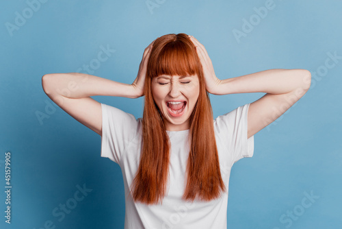 Photo of upset young woman arms close ears isolated on blue background