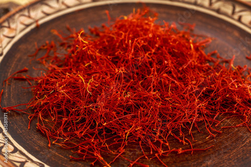 A large number of dry saffron stamens are scattered on a porcelain plate.