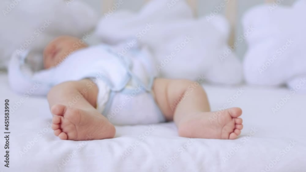 the feet of a small child lying in a crib on a white cotton bed at home, the heels of a newborn baby the feet of a small child lying in a crib on a white cotton bed at home, the heels of a newborn baby