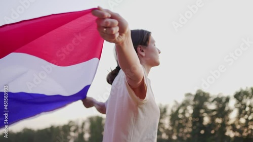 France Day. A French woman with the national flag walks into a field at sunset