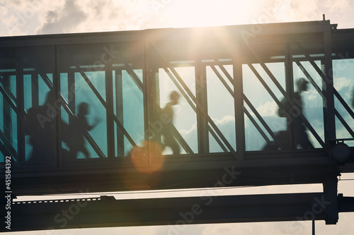 Silhouettes of people walking at busy airport. Passengers walking inside boarding bridge. . photo