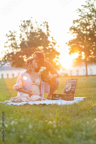Beautiful pregnant young couple having a picnic at sunset