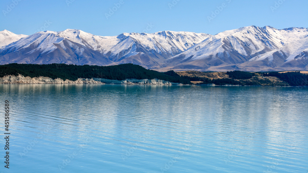 Unique blue water of a lake reflecting an ice covered mountain range