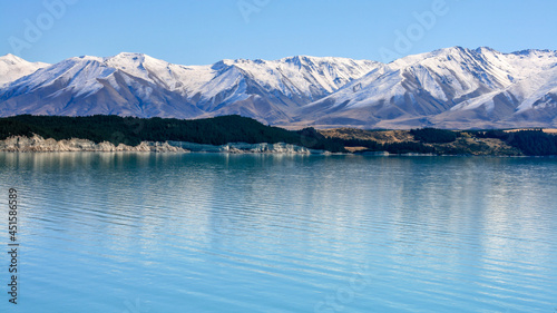 Unique blue water of a lake reflecting an ice covered mountain range