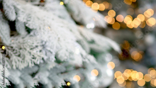 Banner with Christmas blurred background where snow-covered branches of fir and bokeh lights in the background. New year concept
