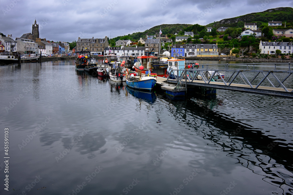 In Tarbert, on a grey and overcast afternoon, boats are moored in the harbour