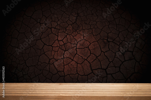 empty wooden table on background of empty dark cracked wall, with focal light