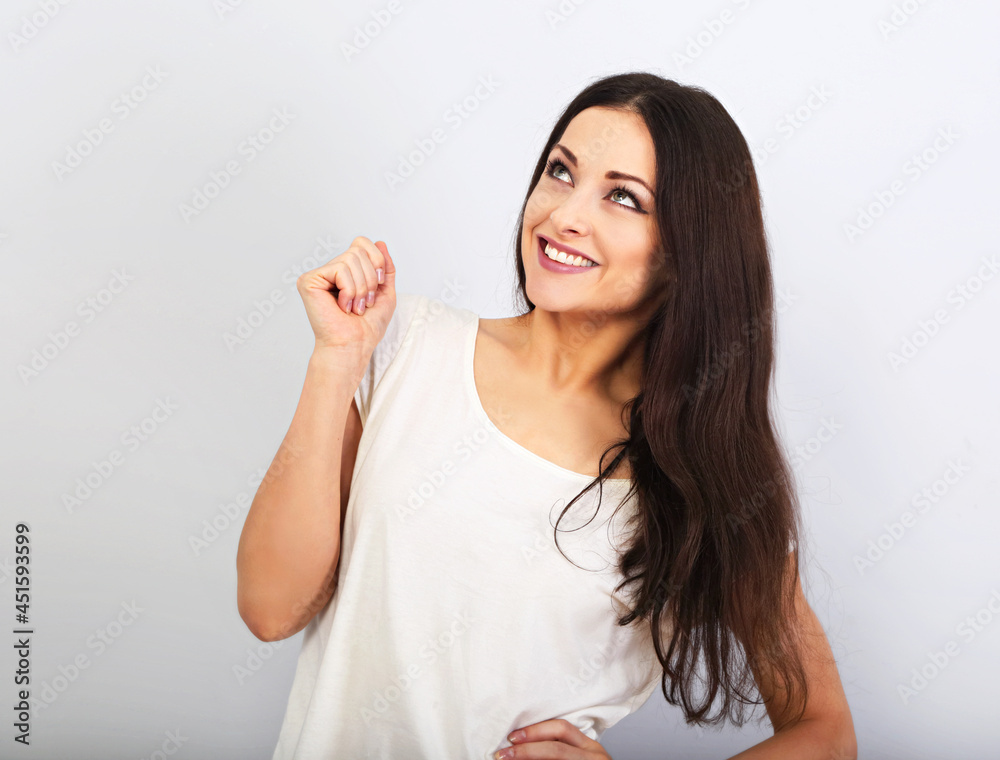 Beautiful young casual cute smiling woman on blue background looking up and thinking. Closeup portrait Beautiful young casual cute smiling woman on blue background looking up and thinking. Closeup portrait
