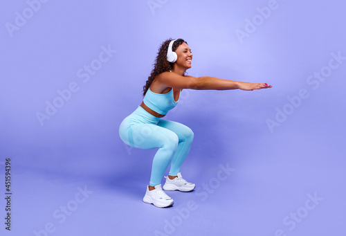 African American woman doing simple sports exercises stretching the muscles of her body, being in a good mood,