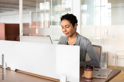 mixed race businesswoman working and typing on laptop at desk .