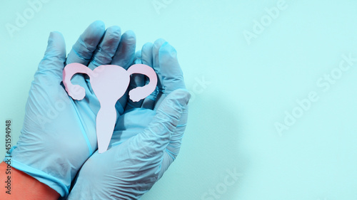 Female reproductive health concept. hand holding uterus shape made frome paper on pink background. Awareness of uterus illness such as endometriosis, PCOS, STDs or gynecologic cancer.