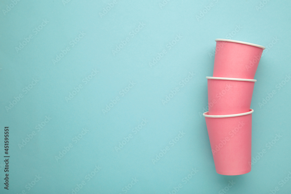 Disposable pink paper cups on blue background. Top view. Disposable pink paper cups on blue background. Top view.