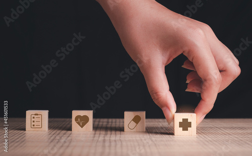 Healthcare medical, Insurance concept. Hand hold health service Icon on wood block cube arranging for plan life.