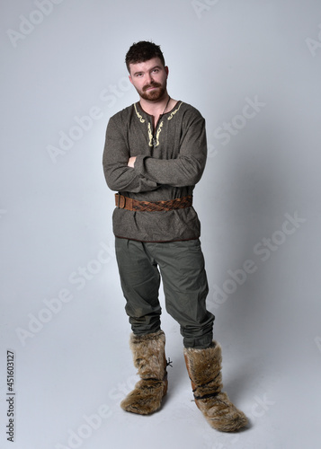 Full length  portrait of  young handsome man  wearing  medieval Celtic adventurer costume.  Standing pose isolated on studio background. © faestock