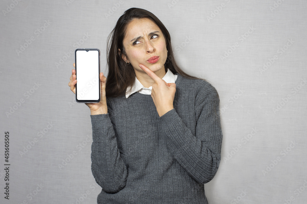 Mujer dudosa sosteniendo celular. Fondo blanco. Mujer dudosa sosteniendo celular. Fondo blanco.