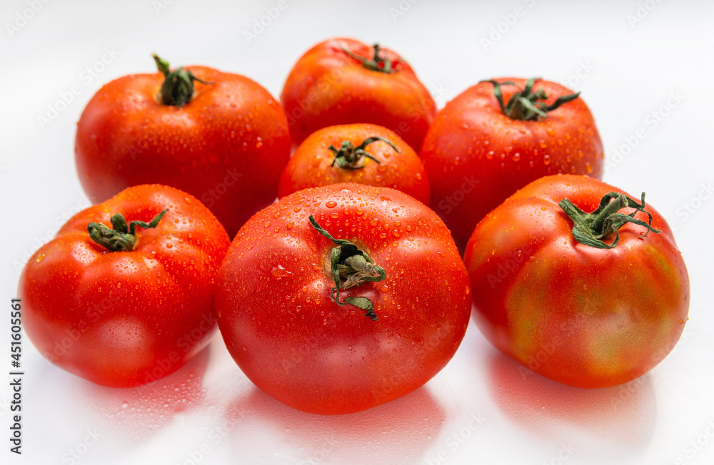 Red ripe tomatoes with water drops on a white background Red ripe tomatoes with water drops on a white background