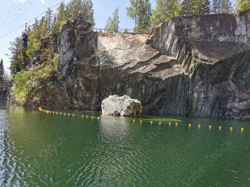 View of the rocky shores, the huge stone and the emerald water of the Marble Canyon in the Ruskeala Mountain Park on a sunny summer day.
